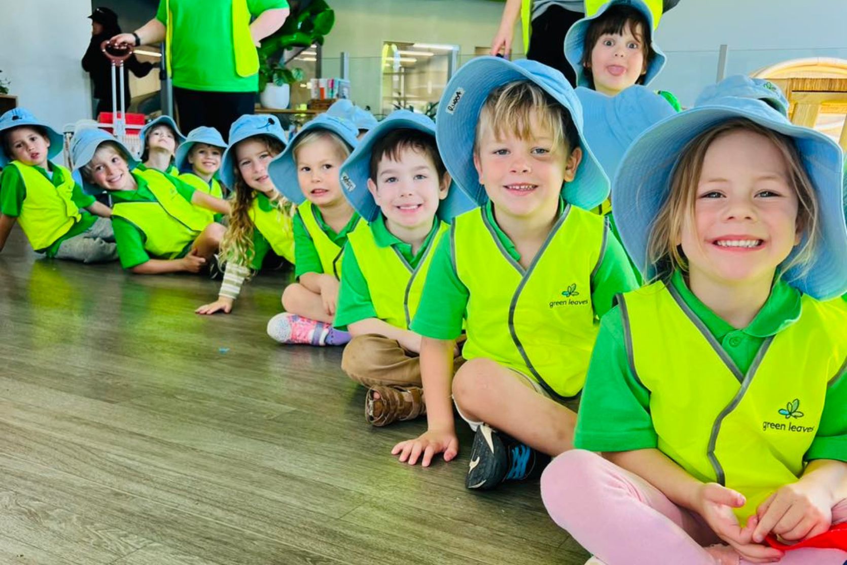 smiling children getting ready for green leaves excursion with high vis jackets and sun smart hats