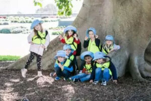 group of children posing in front of tree trunk